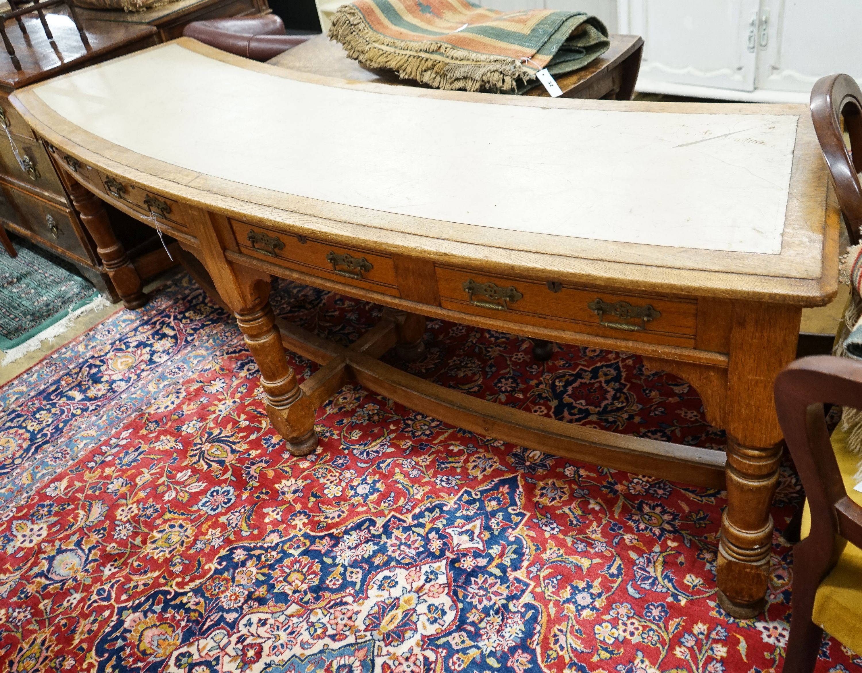 A late Victorian oak four drawer library table of curved rectangular form, length 240cm, depth 60cm, height 80cm